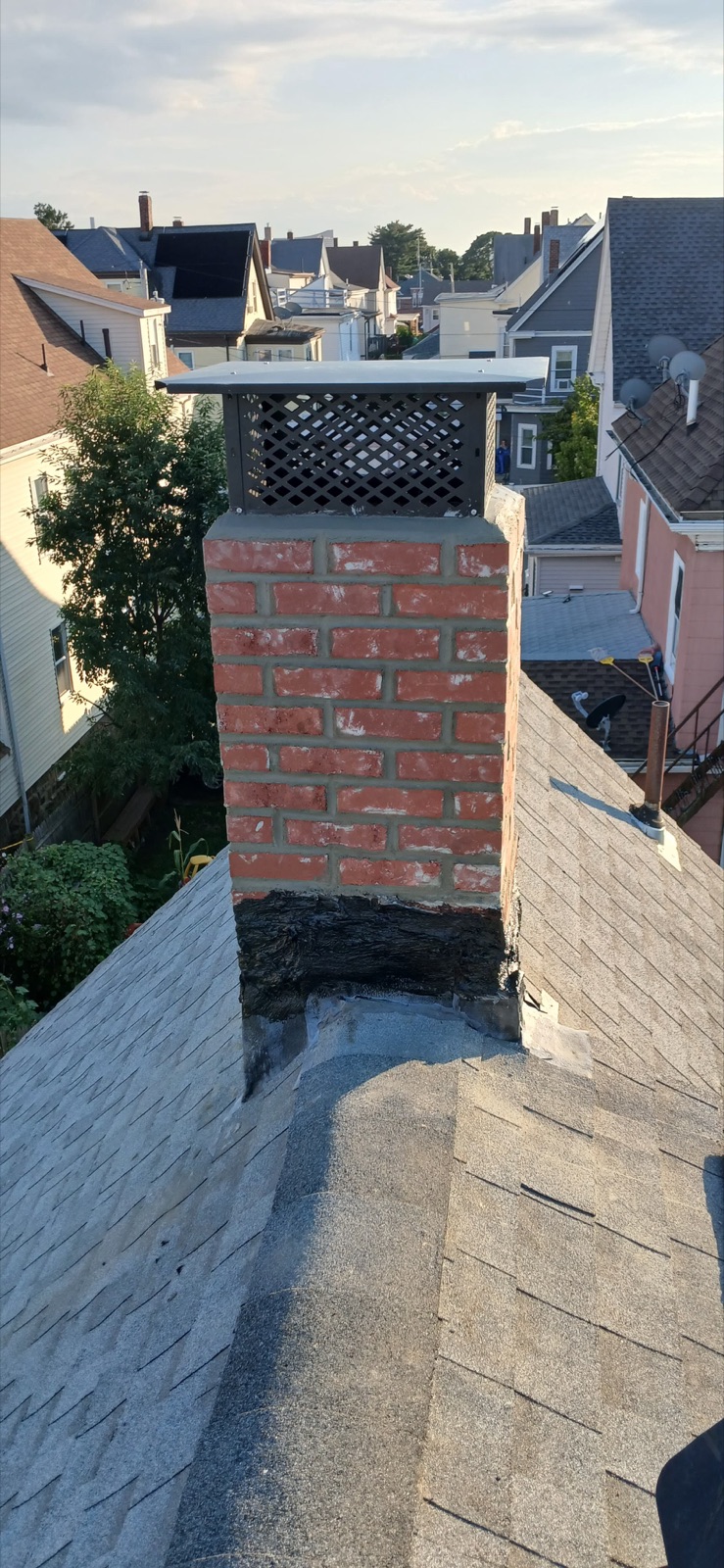 Completed brick chimney with full-coverage cap and roofline in Everett MA