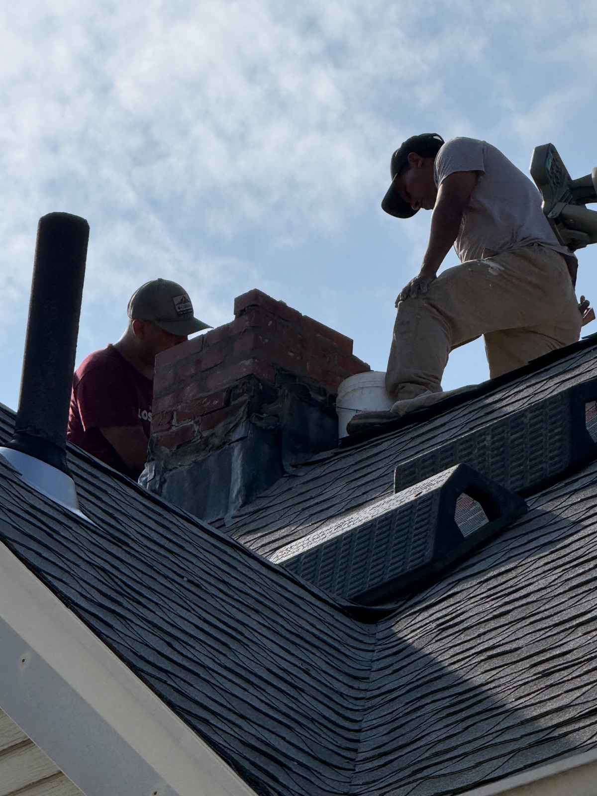 Crew rebuilding the brick chimney above the Everett roofline