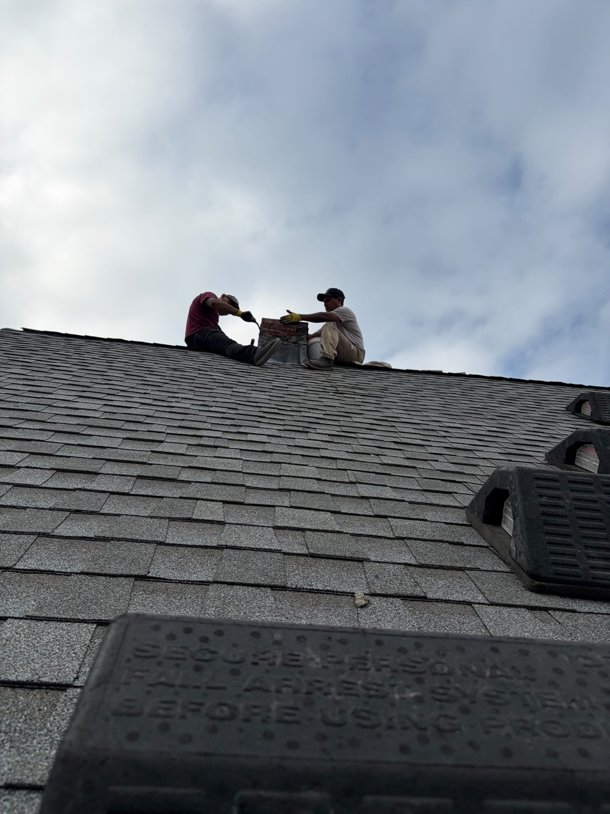 Two crew members rebuilding the chimney at the roofline in Everett MA