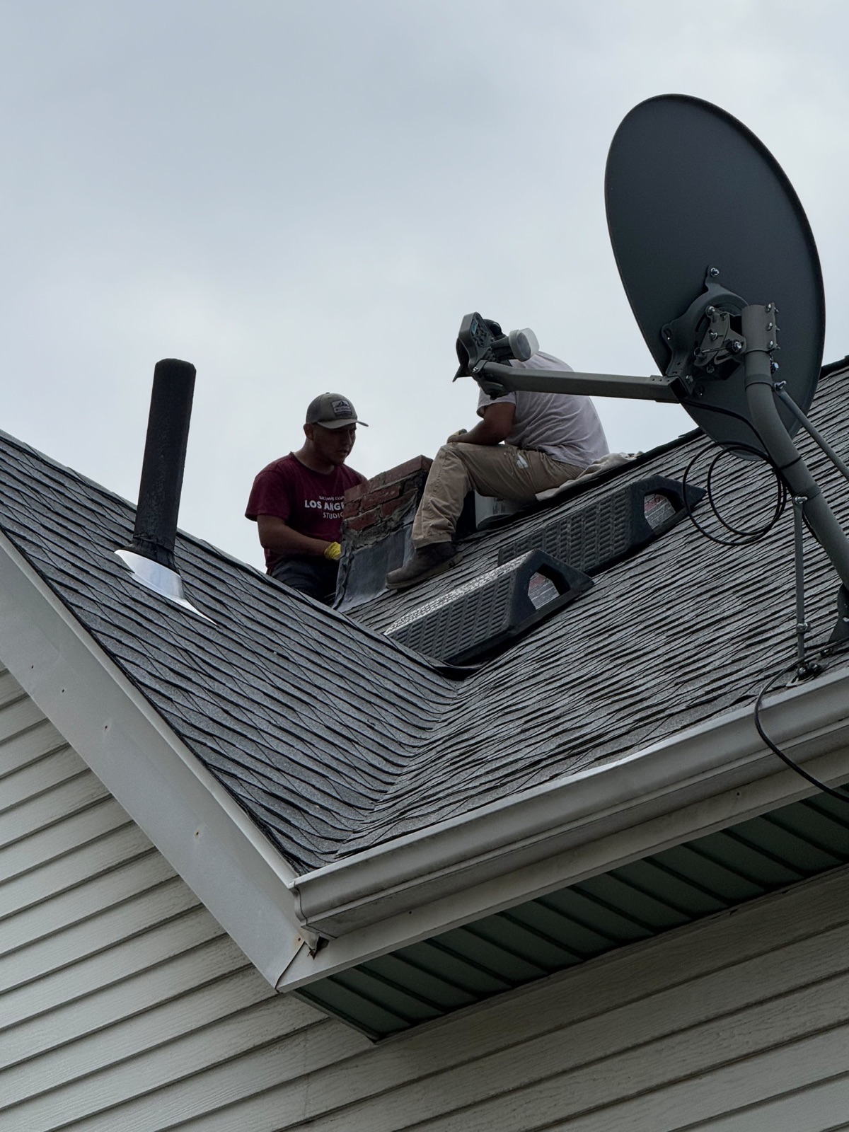 Crew repairing the brick chimney beside the roof vents