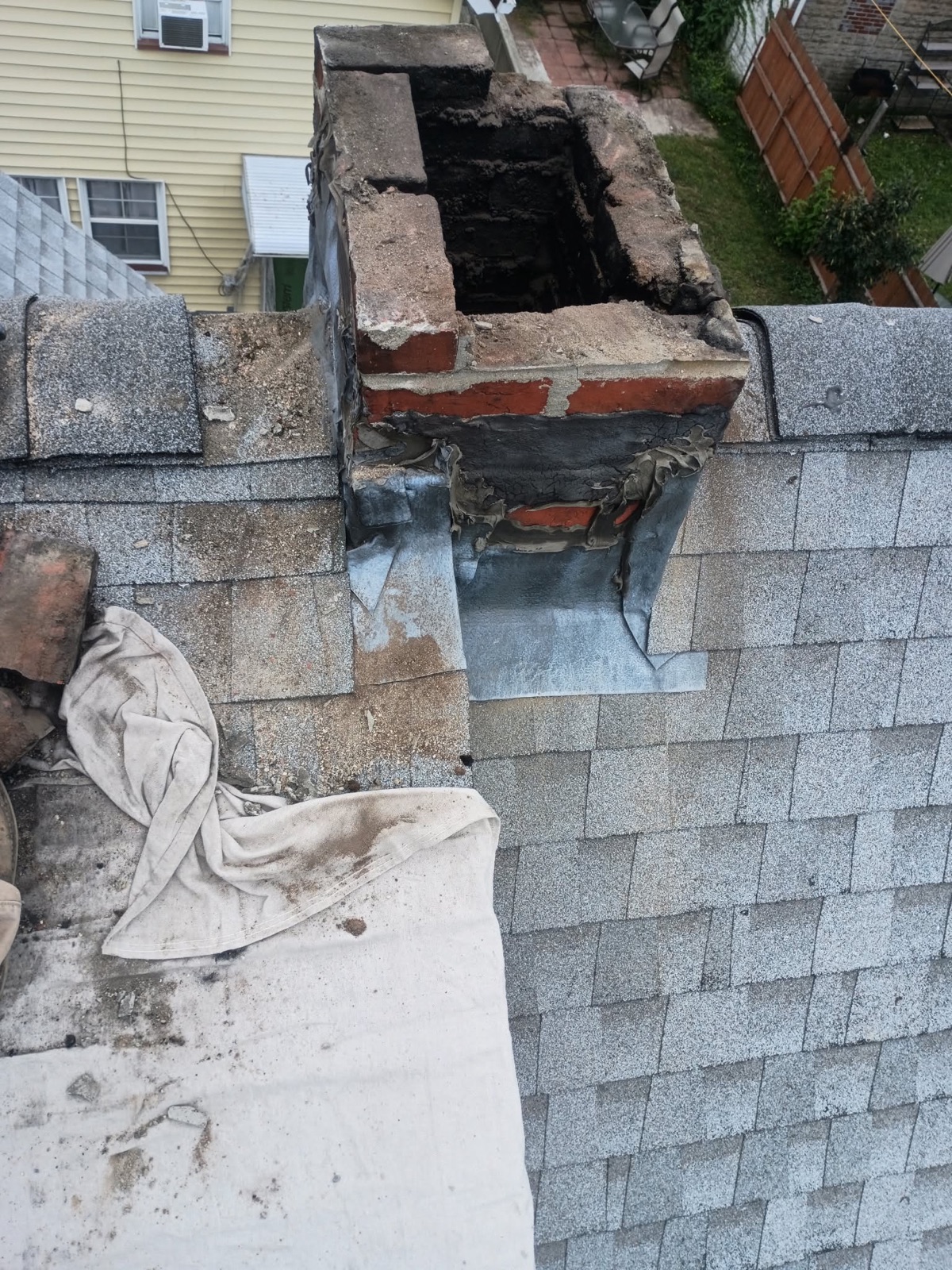 Damaged chimney top before roofline masonry work in Everett MA