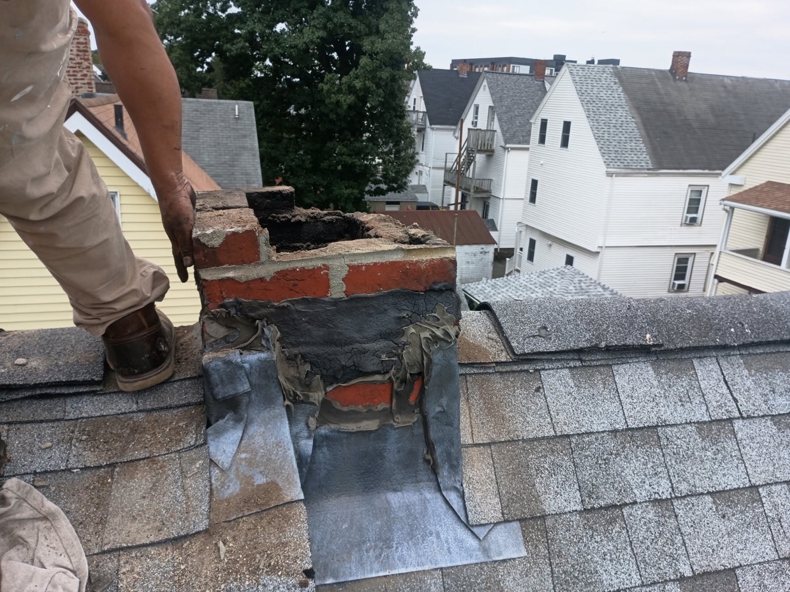 Deteriorated brick chimney and old flashing before the Everett rebuild