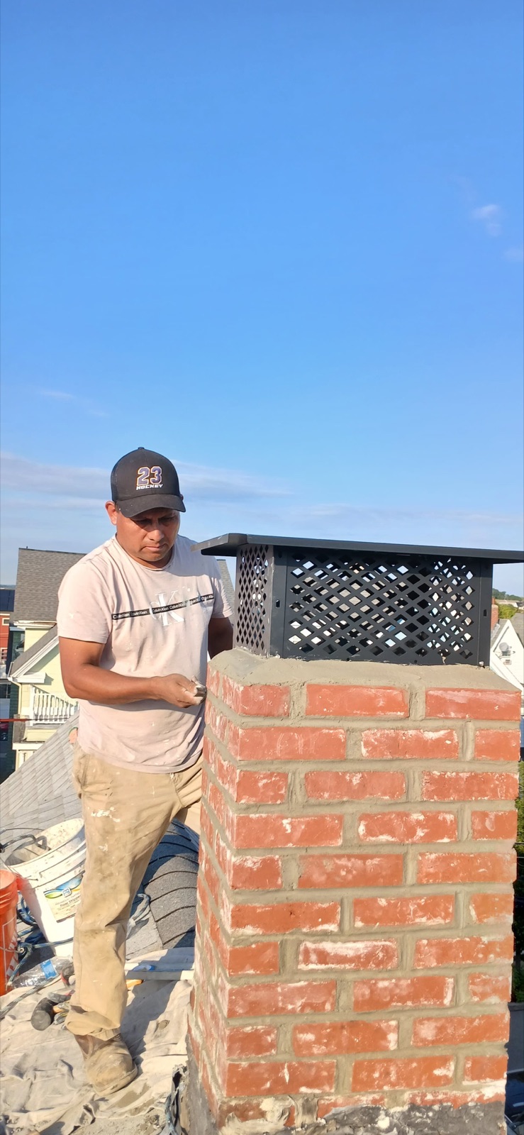 Mason finishing the rebuilt brick chimney below its new cap